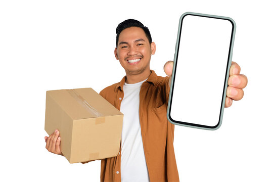 Happy young Asian man in casual shirt holding smartphone with blank screen and cardboard box isolated on transparent background - Powered by Adobe
