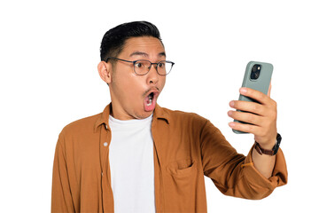Surprised young Asian man in casual shirt using mobile phone with open mouth, reading great news...