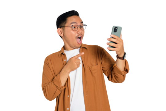Surprised young Asian man in casual shirt using mobile phone with open mouth, reading great news message isolated on transparent background