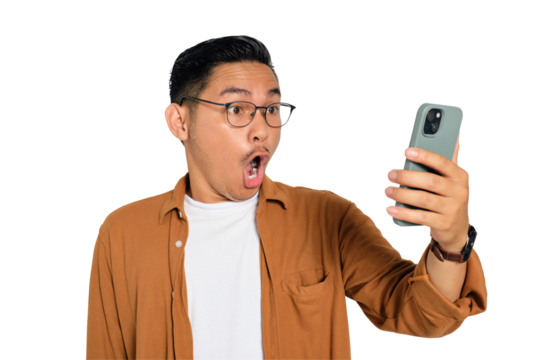 Surprised young Asian man in casual shirt using mobile phone with open mouth, reading great news message isolated on transparent background