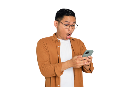 Surprised young Asian man in casual shirt using mobile phone with open mouth, reading great news message isolated on transparent background
