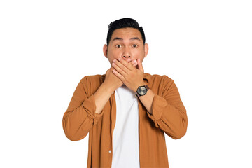 Surprised young Asian man in casual shirt covering mouth with hand, looking at camera with amazed...