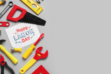 Toy construction tools and greeting card with text HAPPY LABOR DAY on grey background. Labor Day celebration