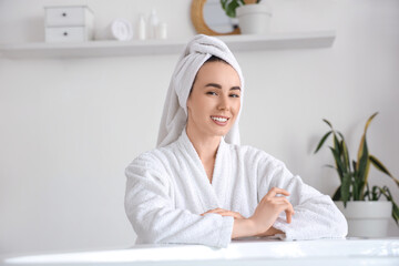 Young woman in soft bathrobe after shower at home