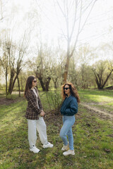 Fototapeta premium Women Engaging in Conversation Outdoors in a Sunny Forest Setting