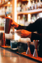 Professional Bartender Mixing a Vibrant Cocktail in a Modern Bar Setting