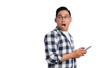 Surprised young Asian man in casual shirt holding smartphone and looking aside at copy space isolated on transparent background