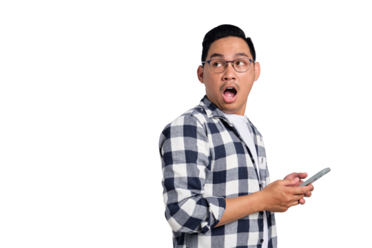 Surprised young Asian man in casual shirt holding smartphone and looking aside at copy space isolated on transparent background