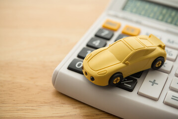 Simple car toy on calculator with wooden table copy space. Money savings management and planning for buying new or used car, car loan payment, insurance, tax, repair, car for cash and so on concept.