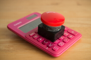 Closeup red emergency button on calculator background. Financial crisis, bankrupt, loss, refinancing, debt restructuring, stop payment, risk management and so on concept.