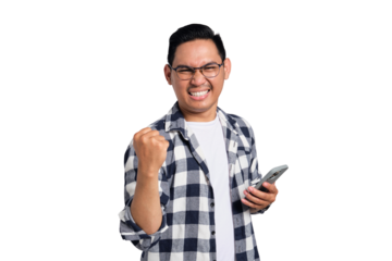 Excited young Asian man in casual shirt using smartphone for trading or chatting, making winning gesture isolated on transparent background