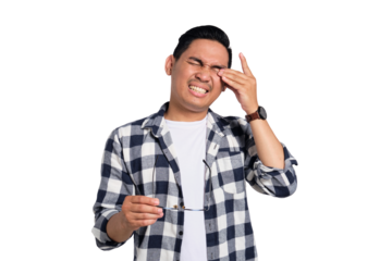 Tired young Asian man in casual shirt taking off glasses, feeling eye strain after work isolated on transparent background