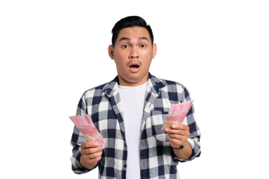 Surprised young Asian man in casual shirt holding money and looking at camera with confused expression isolated on transparent background