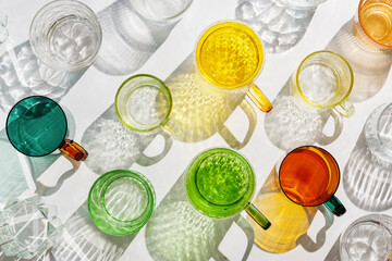 Vibrant set of colorful glass cups on white background, casting artistic light reflections and...