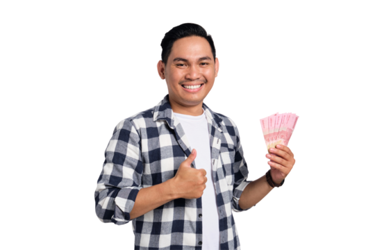 Smiling young Asian man in casual shirt holding money and showing thumbs up isolated on transparent background. Profit and wealth concept