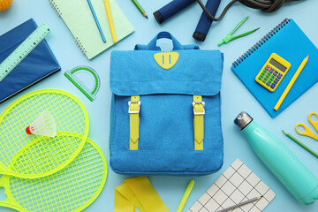 Composition with backpack, school supplies and sports equipment on blue background