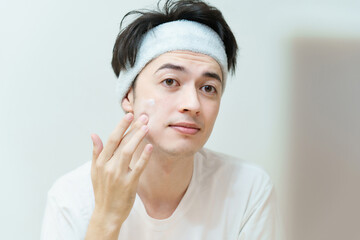 顔にクリームを塗る若い男性