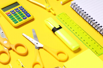 Composition with calculator and different school stationery on yellow background, closeup