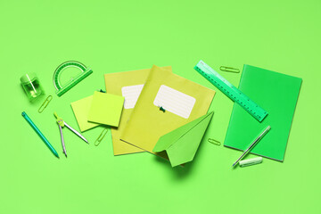 Composition with paper airplane and different school stationery on green background