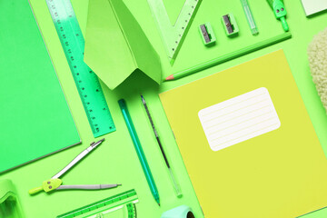 Composition with paper airplane and different school stationery on green background, closeup
