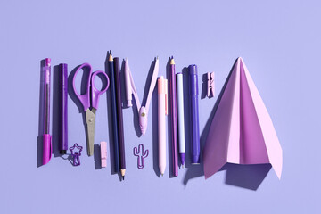 Fototapeta premium Composition with paper airplane and different school stationery on lilac background, closeup