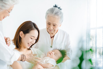 赤ちゃんを抱っこするお母さんと2人のシニア女性