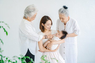 Obraz premium 赤ちゃんを抱っこするお母さんと2人のシニア女性