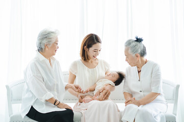 赤ちゃんを抱っこするお母さんと2人のシニア女性