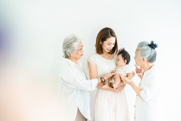 赤ちゃんを抱っこするお母さんと2人のシニア女性