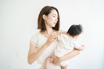 赤ちゃんを抱えて、疲れた表情をするお母さん