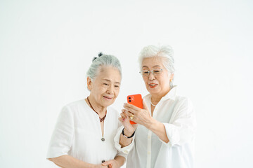 笑顔でスマートフォンの画面を見るシニア女性たち