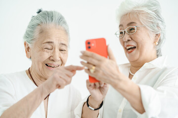 笑顔でスマートフォンの画面を見るシニア女性たち