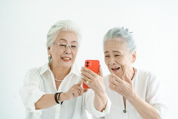 笑顔でスマートフォンの画面を見るシニア女性たち