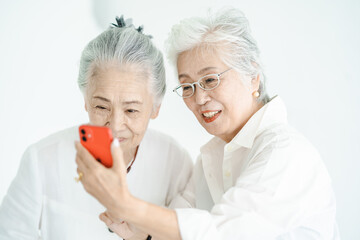 笑顔でスマートフォンの画面を見るシニア女性たち