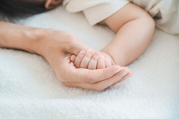 赤ちゃんの手を支えるお母さんの手