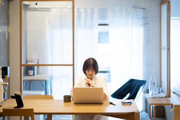 自宅の部屋でノートPCを操作する若い女性