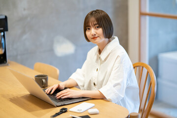 自宅の部屋でノートPCを操作する若い女性