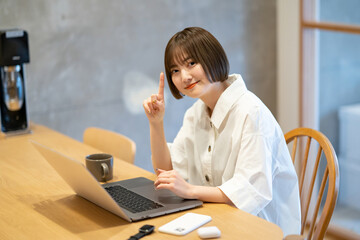 自宅の部屋でノートPCを操作する若い女性