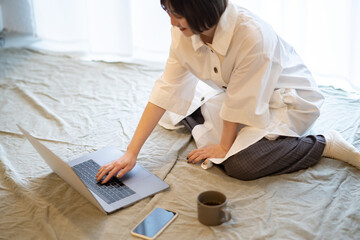 自宅の部屋でリラックスした雰囲気でノートPCを見る女性
