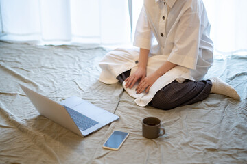 自宅の部屋でリラックスした雰囲気でノートPCを見る女性