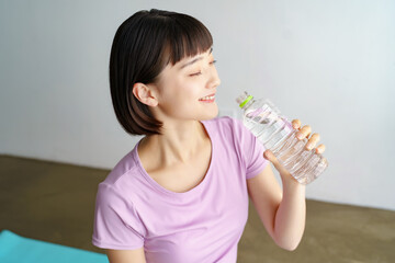 スポーツウェア姿で水分補給をする女性