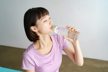 スポーツウェア姿で水分補給をする女性