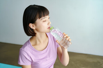 スポーツウェア姿で水分補給をする女性