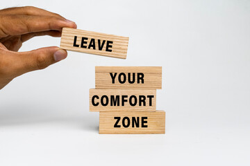 male hand put leave your comfort zone words on wooden blocks isolated on white background