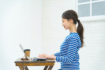 部屋でタブレットPCを操作する若い女性
