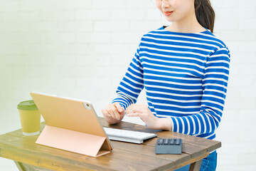 部屋でタブレットPCを操作する若い女性