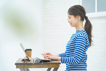 部屋でタブレットPCを操作する若い女性
