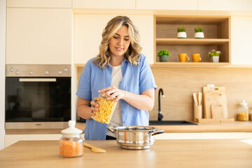 A woman prepares pasta in a stylish, modern kitchen highlighting the joy of cooking and home-cooked...