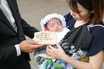 In June 2025, a young Japanese mother holds her one-month-old baby dressed in a ceremonial kimono...