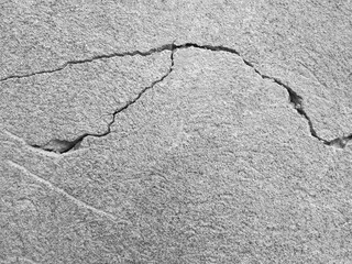 Thin winding deep crack on old gray concrete wall. Abstract image of horizontal cleft. Several of ascending cracked line. Black and white photo. Close up. Selective focus. Copy space for text.
